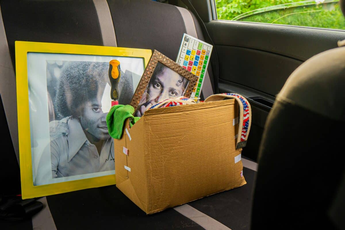 A cardboard box filled with framed photos and packed items sitting on the back seat of a car during a home clean-out.
